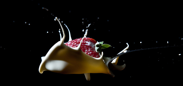 Imagen de una fresa sobre una cuchara de nata