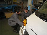 Lorenzo y María mirando la aleta delantera de un vehículo.