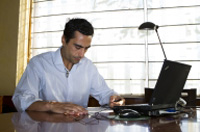Ramón con camisa blanca delante del portatil en su mesa de trabajo.