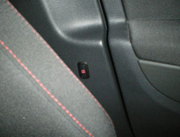 Pulsador interior de alarma en marco de puerta para su desconexión al cerrar el vehículo con pasajeros dentro.