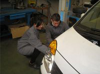 Lorenzo y María mirando la aleta delantera de un vehículo.