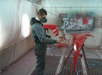 Lorenzo pintando una aleta de un vehículo.