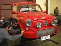María y Lorenzo mirando los bajos de la rueda de un vehículo.