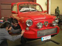 María y Lorenzo mirando la rueda de un vehículo.