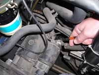 En la fotografía se ve un alumno desmontando  el motor de arranque  de un coche.