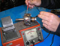 En la fotografía se ve un como se comprueba el aislamiento a masa del rotor de un alternador mediante un comprobador de inducidos.