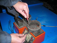 En la fotografía se ve un como se comprueba el aislamiento a masa del estator de un alternador mediante un comprobador de inducidos.