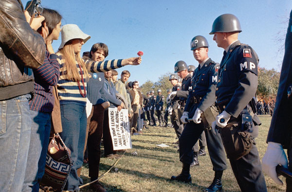 A female demonstrator offers a flower to military police