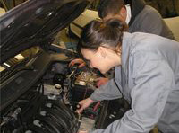 María y Lorenzo revisando el motor de un vehículo.