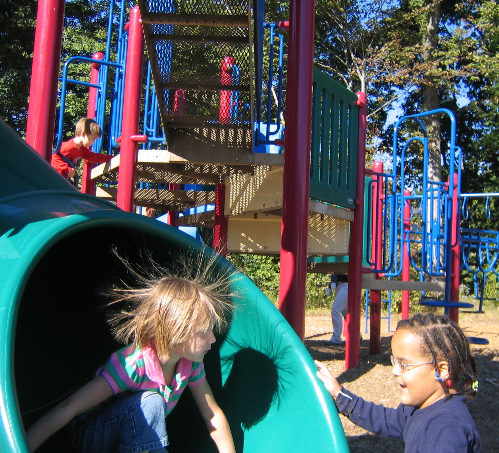 Foto de unos ni&ntilde;os jugando en un tobog&aacute;n con el pelo "electrizado".