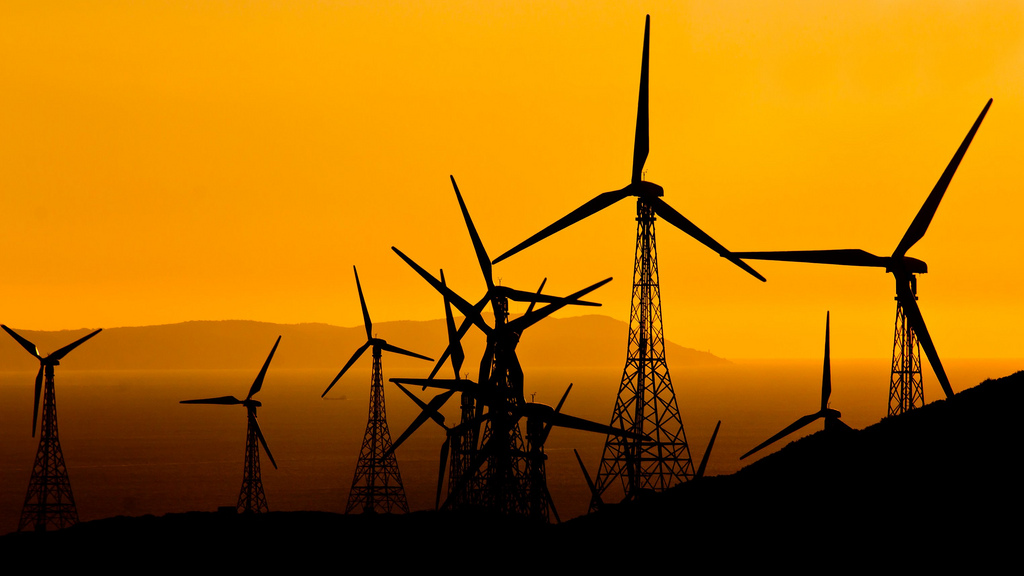 Foto de un anochecer con la vista de un grupo de aerogeneradores.