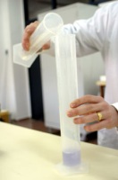 Foto de un trasvase de líquido de una probeta pequeña a un más grande.