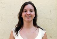 Vemos a una joven de cabello negro y largo. Viste una camiseta de tirantes color beige. 