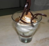 Se puede ver un  postre en una copa de cristal a base de merengue, con decoración de chocolate.