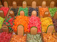 Se pueden ver varias gominolas y otros dulces en un expositor mostrando sus vivos colores, donde encontramos naranjas, verdes, rojos y amarillos.