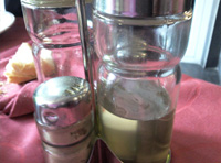 En la imagen podemos ver unas vinagreras de restaurante, una de las cuales contiene un líquido semitransparente, color amarillo muy pálido donde se aprecia claramente una turbidez blanquecina.