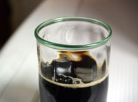 Podemos apreciar un vaso de cerveza muy oscura.