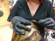 Prueba de resistencia-distensión. Se ve la imagen de una profesional vestida de negro que sujeta entre sus dedos índice y pulgar, un mechón de cabello sin tensar.
