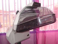  Imagen de un aparato gris en forma de casco trasnparente, delante de una cortina color violeta