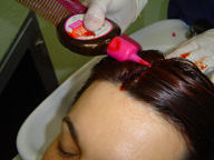  Imagen de una chica en el lavacabezas a la que una profesional está aplicando una coloración directa.