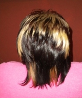 Imagen de un cabello, visto por detrás, con grandes bloques de color marrón oscuro y rubio dorado. La cliente tiene una capa rosa sobre los hombros,y detrás se ve una pared de color marrón.