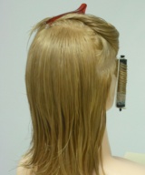 Se aprecia un maniquí, con un bigudí enrollado en espiral y de forma vertical. 