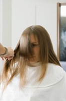 Se observa un profesional cortando las puntas del cabello de su cliente.