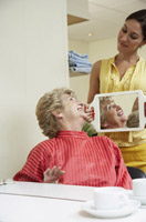 Se ve a una cliente satisfecha de su peinado y a un profesional enseñándole el cabello por detrás con un espejo.