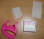 Se puede ver una muñequera de plástico, una caja de papeles de permanente y dos papeles fuera de la caja.