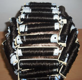 Se aprecia un maniquí con los bigudies puestos en la cabeza, con el montaje clásico.