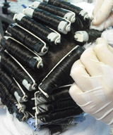 Se puede ver una cabeza con los bigudíes enrollados y unas manos aplicando el líquido con algodón.