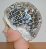 Vista lateral del proceso de permanente rizada y la protección con algodón alrededor de la cara. La cabeza cubierta con gorro de plástico.