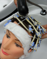 Cabeza con bigudíes, en el lavacabezas, enjuagados por una persona.