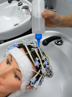 Aplicación de neutralizante, en un cabello de maniquí enrollado con bigudíes. Se observa que está en el lavacabezas.