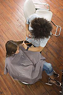 Es la imagen desde el techo de un profesional cortando el cabello a una usuaria.