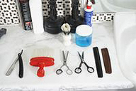 En ella se ven dos tijeras, dos peines de corte, un cepillo para quitar los pelos, una navaja y varios cosméticos al fondo. 