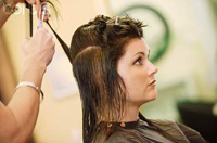 Se ve una imagen de una usuaria a la que le están cortándo el cabello. El profesional sujeta proyectándola.
