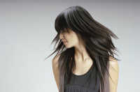 Se ve una mujer con el cabello largo, escalado y desfilado. La foto está hecha en movimiento, se ve el dibujo de las capas de su cabello.