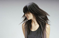 Melena larga con movimiento. Se ve una mujer con el cabello largo, escalado y desfilado. La foto está hecha en movimiento, se ve el dibujo de las capas de su cabello.