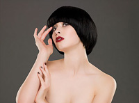 Se ve una mujer con el cabello muy oscuro y la piel muy clara. Lleva el cabello cortado de forma compacta redondeada.