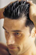 Hombre aplicando cosmético capilar. Se ve un hombre aplicando algún cosmético y colocando su cabello hacia atrás.