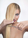 Mujer con cabello de lado para cortar. Se ve una mujer con cabello de lado. Lo sujeta con los dedos para cortarlo con una tijer ella misma.