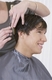 Corte caballero escalado. Se ven las manos de una peluquera cortando el cabello a un usuario.