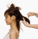 Partición nuca. Se ve una mujer de perfil, lleva el cabello sujeto en varias particiones. La partición de la nuca está suelta y unas manos manipulan el cabello.