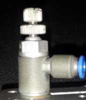 Imagen de un estrangulador de color gris que tiene un tornillo en la parte de arriba para poder regular y la toma de enchufe rápido de color azul