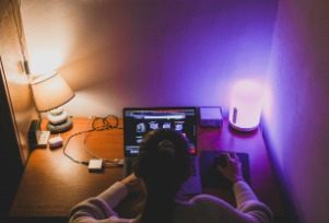 Persoa utilizando un ordenador con dúas lamparas ó seu carón